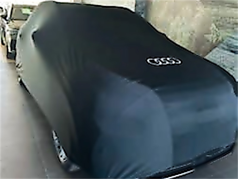 Coche cubierto con una funda textil negra con el logotipo de la marca.