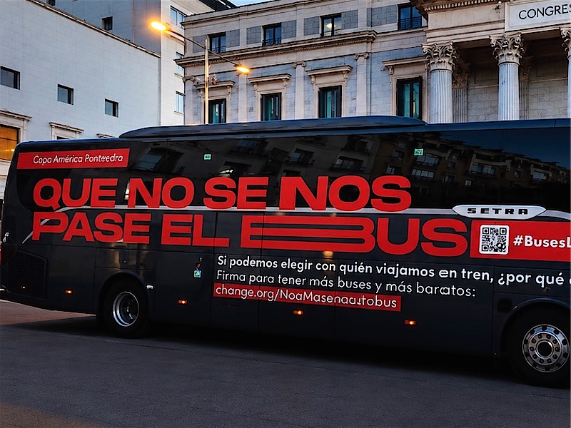Autocar rotulado con una campaña, aparcado frente al Congreso de los Diputados.