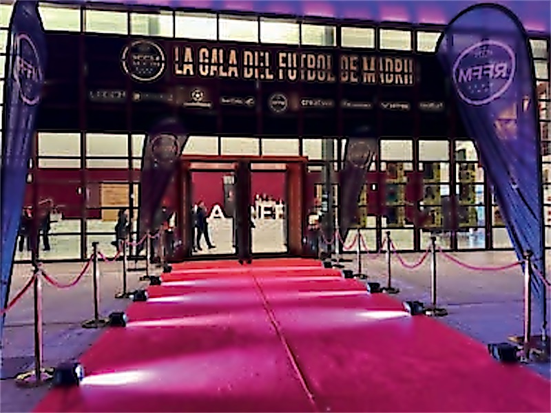 Entrada de una gala con alfombra, photocall y banderas iluminadas.