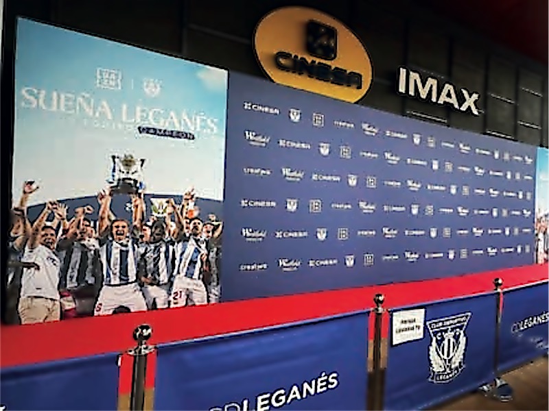 Photocall de gran formato en el vestíbulo de un cine, con la foto de un equipo de fútbol.