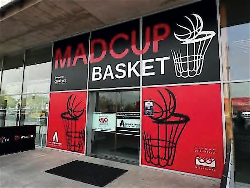 Acceso a un pabellón vestido con los vinilos de un torneo de baloncesto.