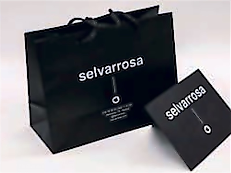 Bolsa de papel negra con asas de cordón y tarjeta con el logotipo de la marca.