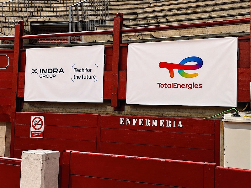 Lonas impresas de dos patrocinadores colgadas sobre la barrera de una plaza de toros.